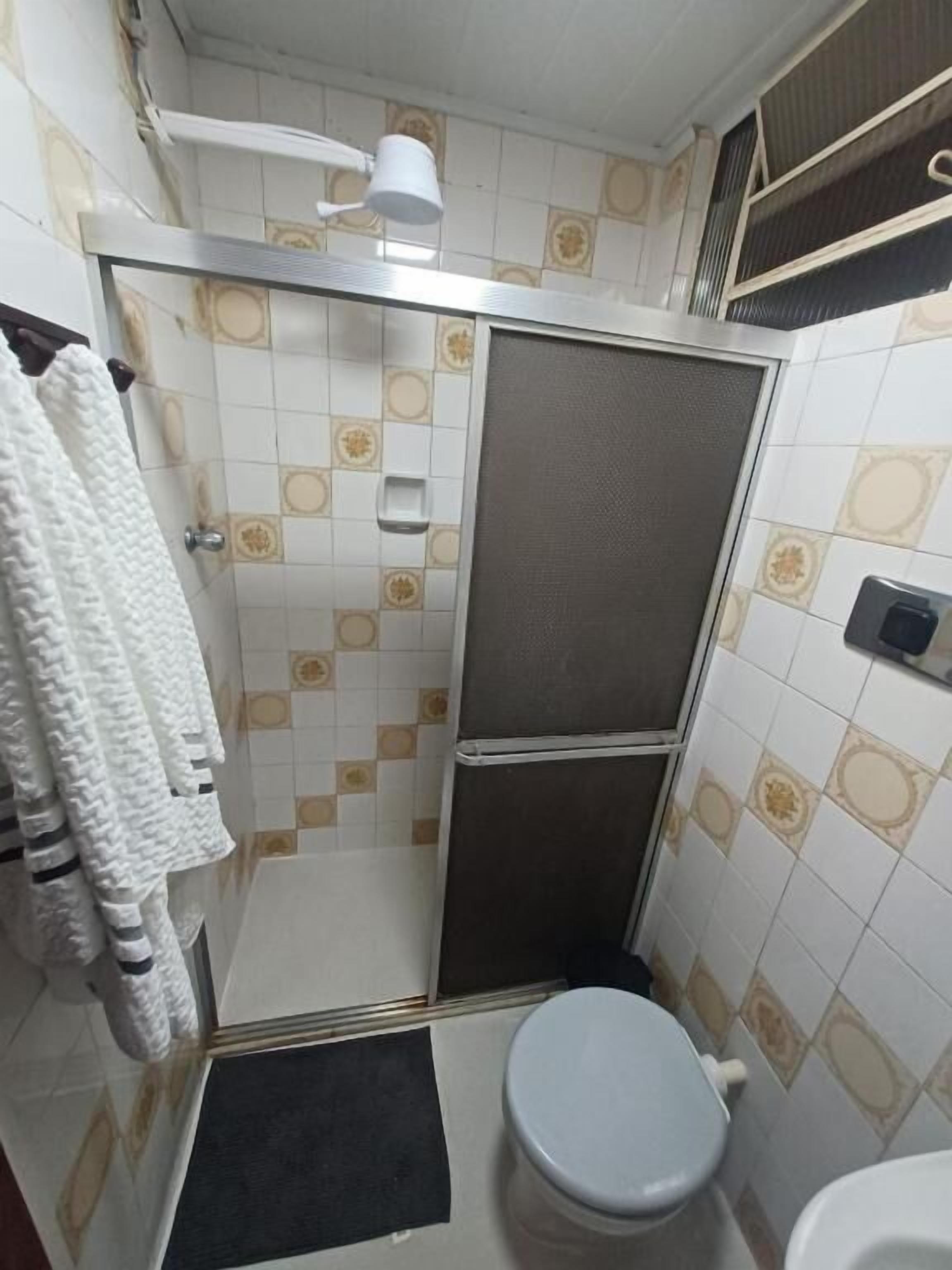 Een kleine badkamer met een douche, toilet en handdoekrek.