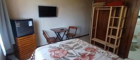 A hotel room with a bed, a TV, a desk, and a chair.