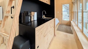 Une cuisine de taille réduite, dotée de meubles en bois, d’un plan de travail noir et d’une machine à café.