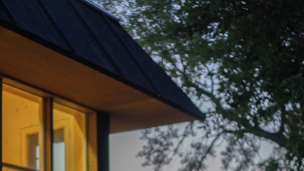 Une terrasse en bois avec un barbecue, entourée de verdure.