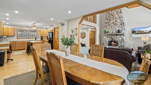 A spacious living area with a fireplace, wooden furniture, and a stone accent wall. - Hot Tub | 5 Minutes to Wilmot Ski Resort  | Game Room (Twin Lakes)