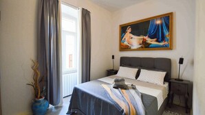 A bedroom with a large bed, a nightstand, a lamp, a potted plant, and a painting on the wall. - Holiday apartment in the city centre (Pula)