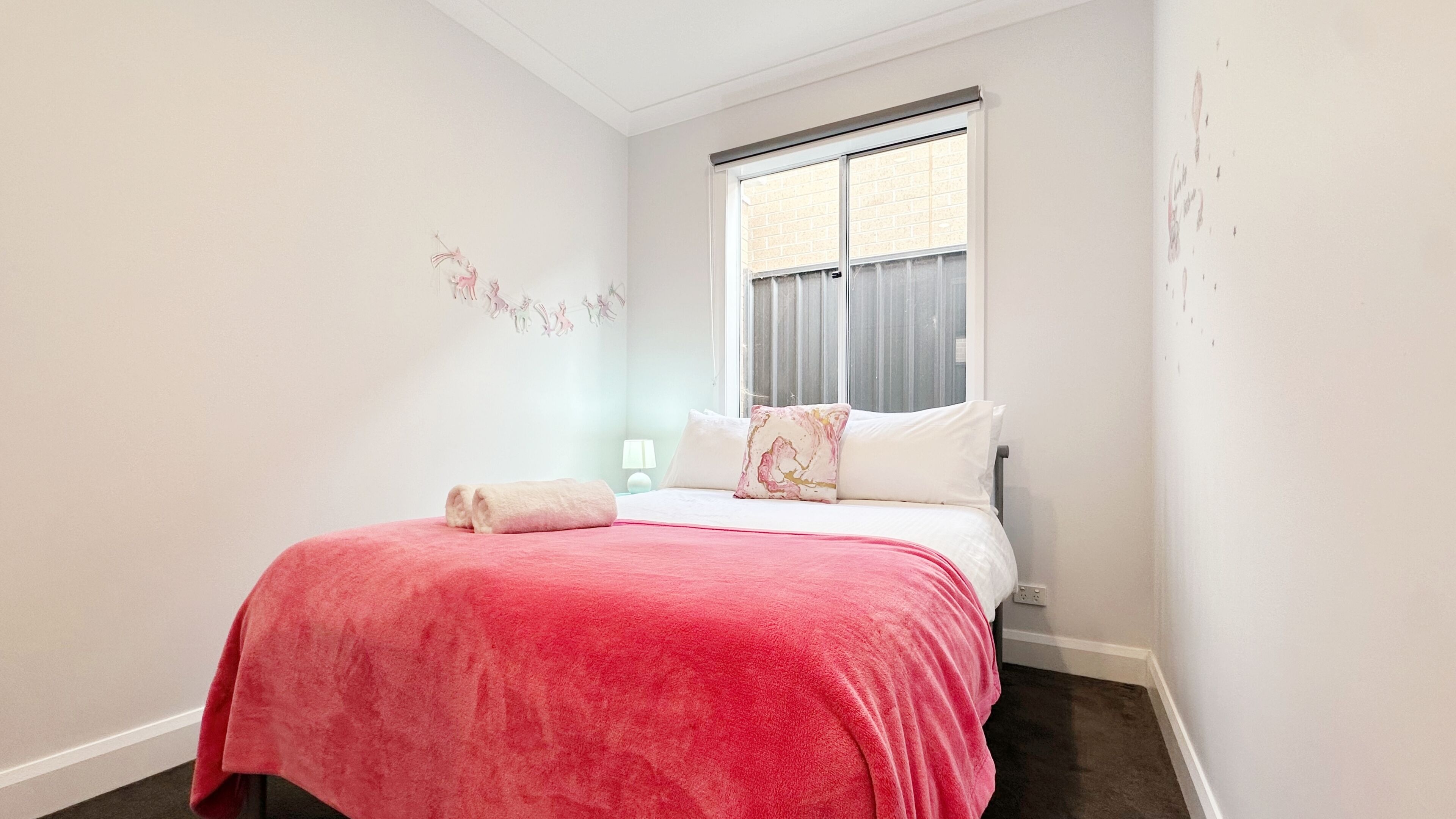 A bedroom with a bed, a window, and a wall decoration.