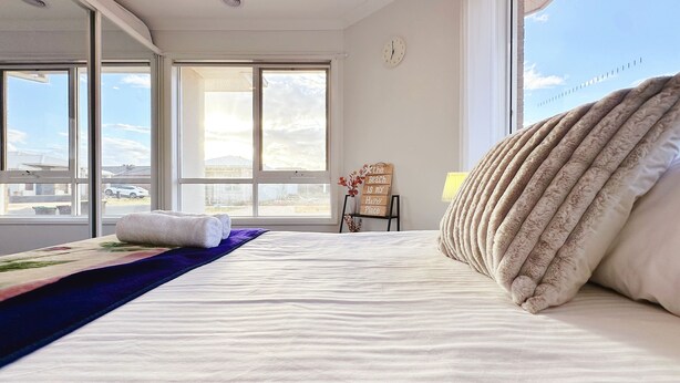Un dormitorio con cama, ventana, reloj y un letrero en la pared.