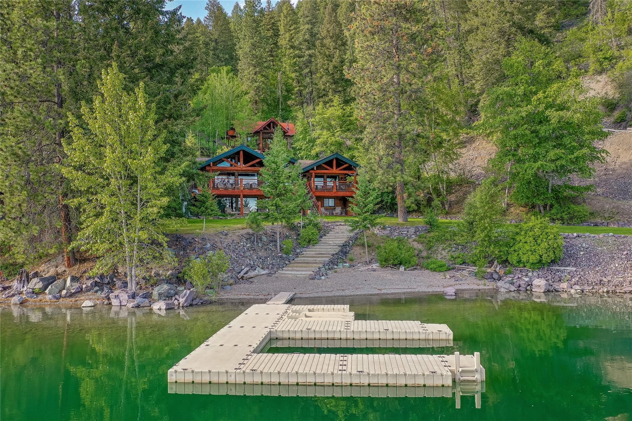 Un chalet comprenant deux bâtiments principaux, un quai et une forêt environnante.