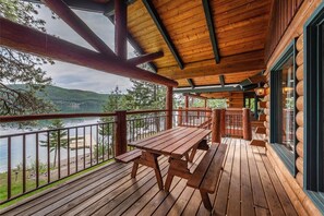 A wooden deck with a table and benches overlooking a lake.