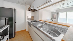 A modern kitchen with a stainless steel sink, a black refrigerator, and a wooden countertop. - E-US NAEBO STATION 207 (Sapporo)