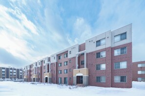Un edificio residencial de varios pisos con fachada de ladrillo, múltiples ventanas y techo plano.