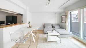 A modern living room with a sofa, a coffee table, and a dining table with chairs. - E-US NAEBO STATION 207 (Sapporo)