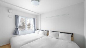 A modern hotel room with a large bed, a window with curtains, and a ceiling light. - E-US NAEBO STATION 207 (Sapporo)