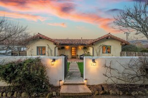 A two-story house with a tiled roof, a front door, and a pathway leading to the entrance. - Spanish Farmhouse Retreat | Gardens + Fireplace (Santa Barbara)