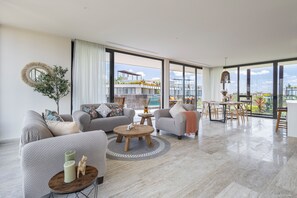 Ein geräumiges Wohnzimmer mit großem Fenster, einem runden Couchtisch und einer Sofagarnitur.