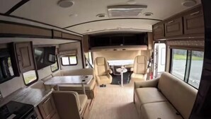 A compact RV interior with a kitchenette, a dining area, and a seating area. - Kenai Riverfront RV Camping & World Class Fishing. (Soldotna)