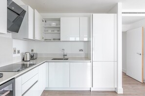 Eine moderne Küche mit weißen Schränken, einer Edelstahl-Spüle und einem eingebauten Backofen.
