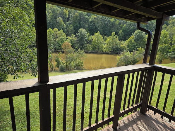 A wooden deck with a view of a lake surrounded by trees.