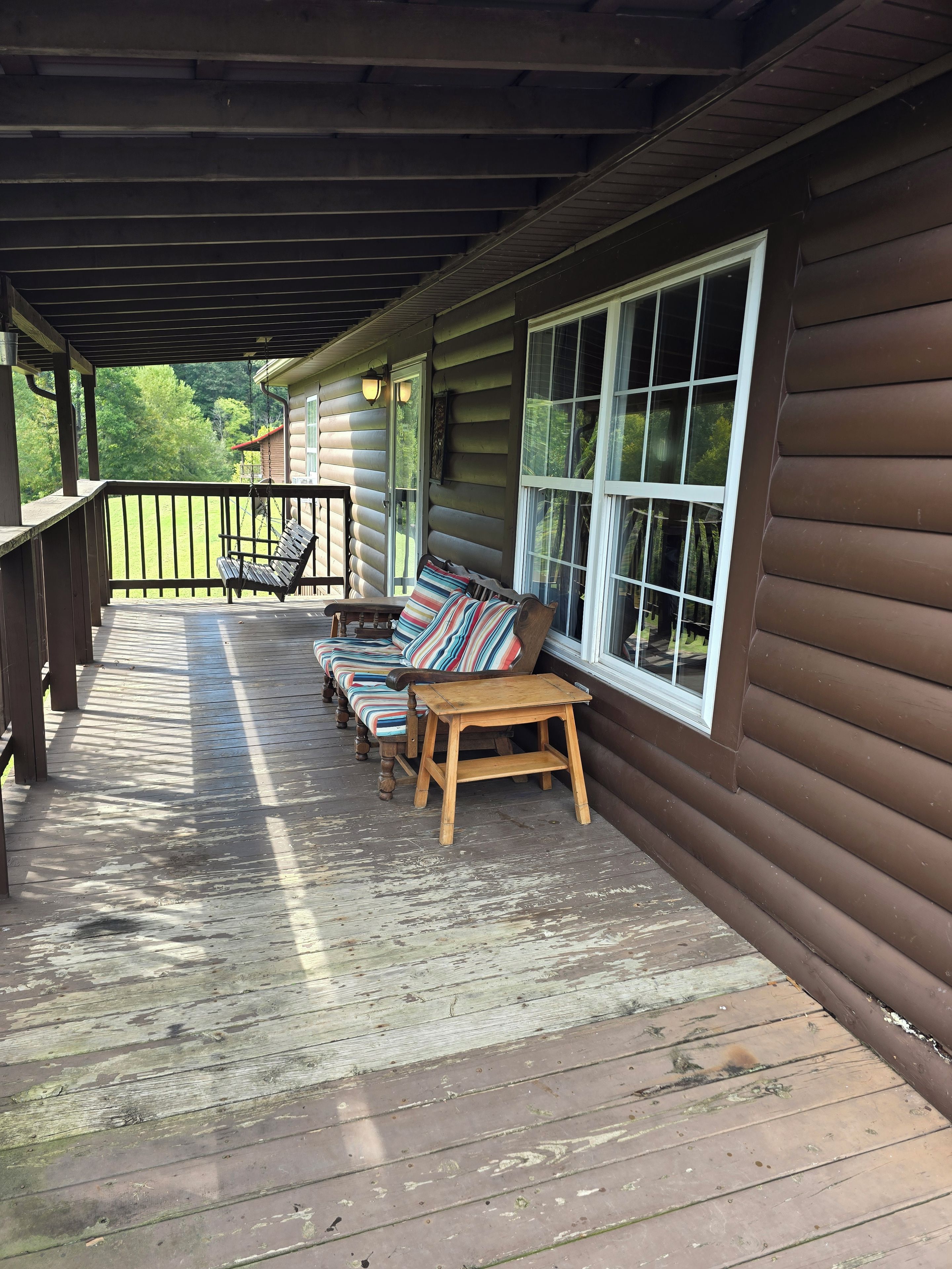 A wooden deck with a bench and a small table, overlooking a green landscape.
