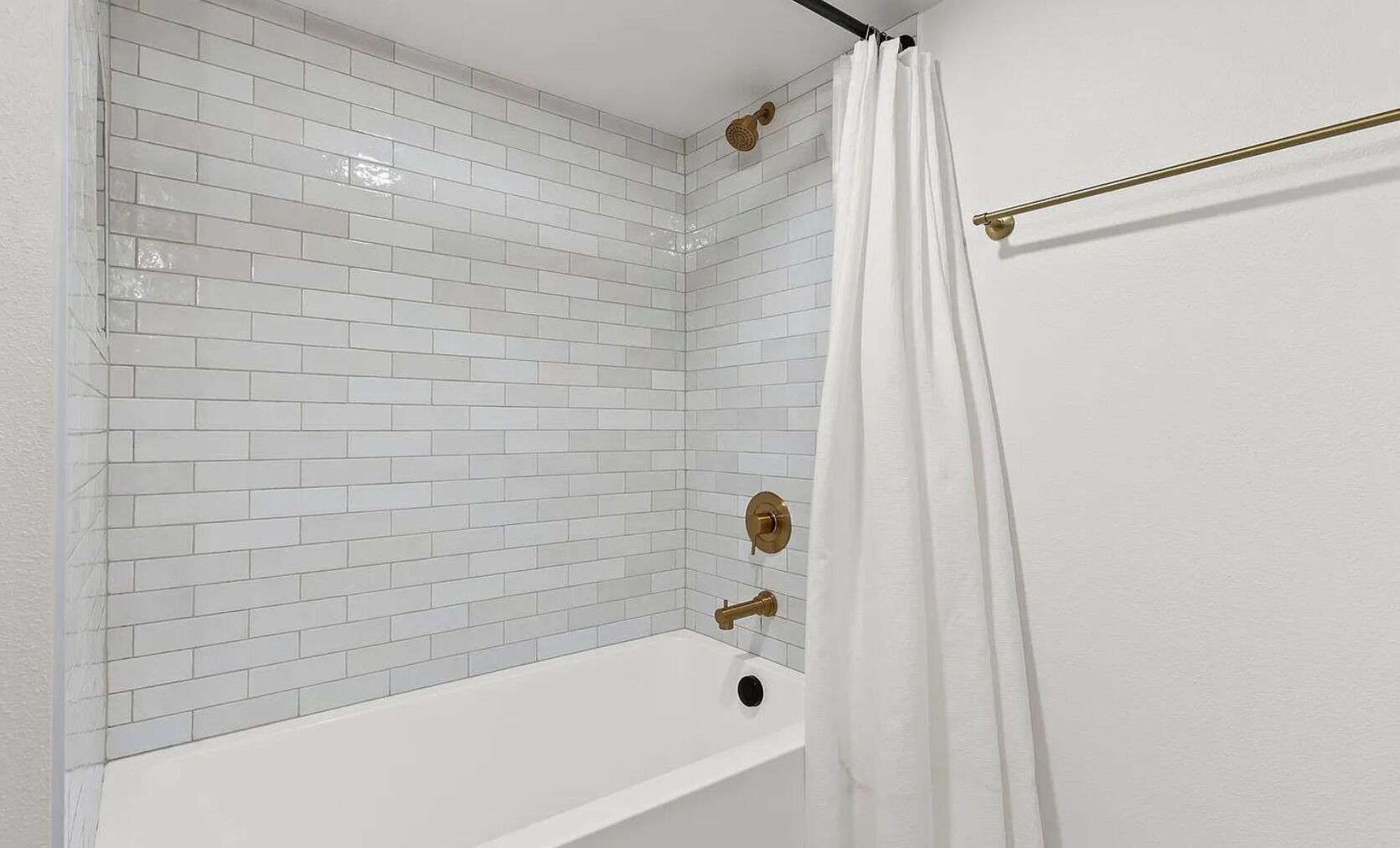 Ein Badezimmer mit weißen Fliesenwänden, einer weißen Badewanne und einer Duschvorhang.
