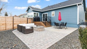 Une maison bleue dotée d’un patio comprenant un canapé, un foyer et une table avec des chaises.