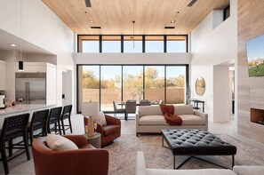 Un interior moderno con cocina, zona de comedor y espacio de estar, con ventanas amplias.