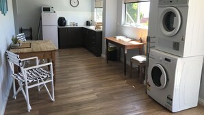 Pieni, käytännöllinen keittiö, jossa on puinen pöytä, tuolit, mikroaaltouuni ja pesukone.