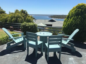 A patio with a round table and four chairs, overlooking a body of water and distant land. - Blackwood Hideaway (Augusta)