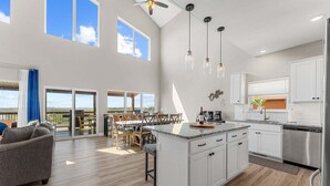 Een ruime keuken met een groot eiland, witte kasten en een eethoek met uitzicht.