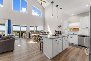 A spacious kitchen with a large island, white cabinetry, and a dining area with a view.