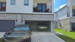 A two-story house with a garage, a parked car, and a balcony with outdoor furniture. - Private Pool at Pershing Flat. 3BR Sleeps 9. 10 mins from NRG . Huge backyard (Houston)