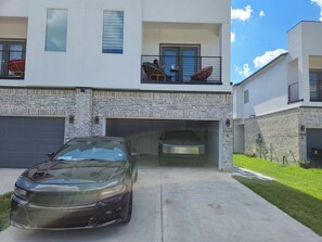 Ein zweistöckiges Haus mit Garage, einem geparkten Auto und einem Balkon mit Gartenmöbeln.