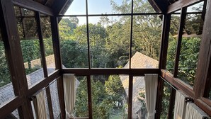 Ein geräumiges Zimmer mit großen Fenstern, einer Holzbalkendecke, einer Couch, einem Tisch und einem Stuhl.