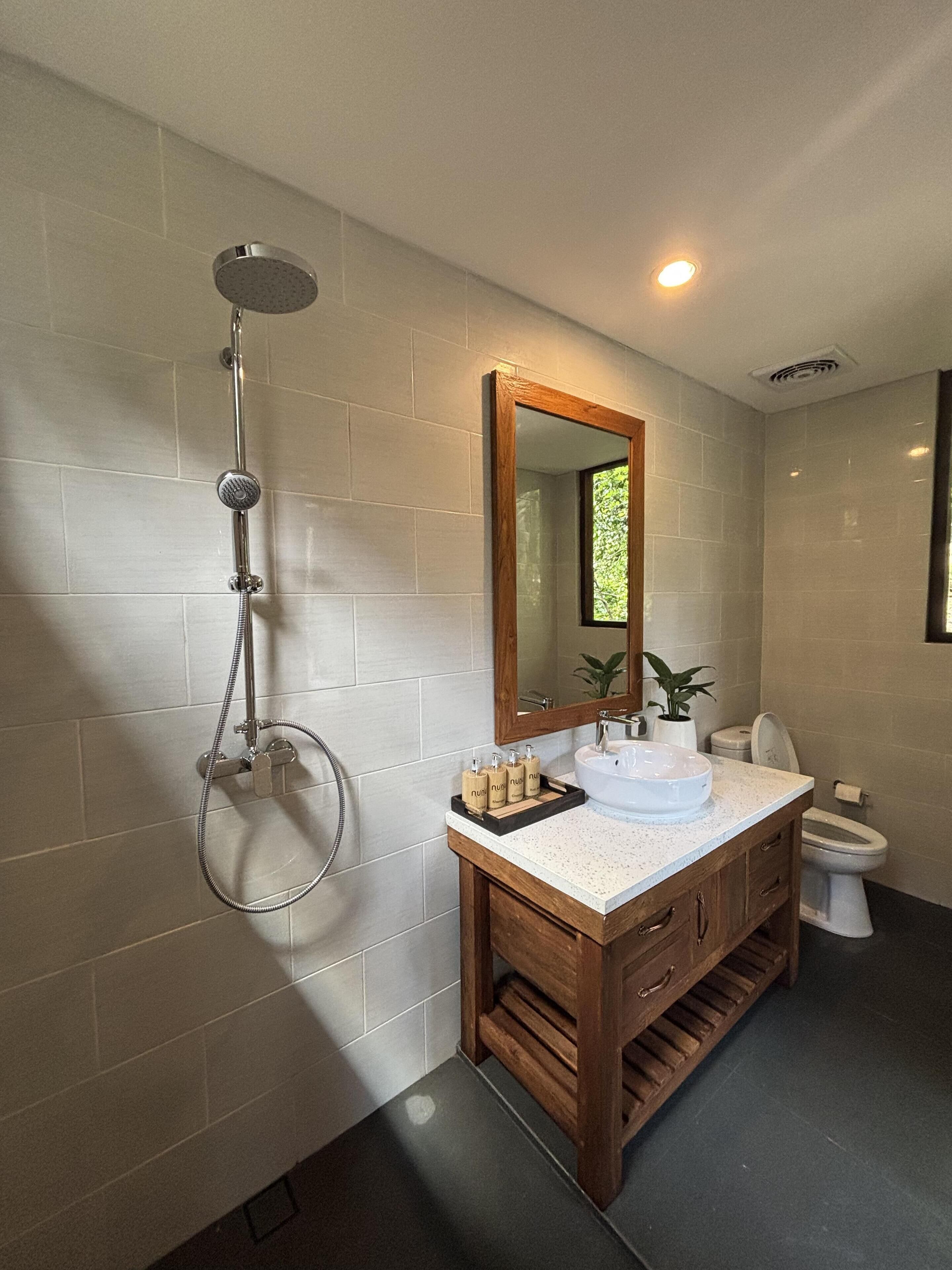 A modern bathroom with a freestanding shower, a wooden vanity, and a large mirror.