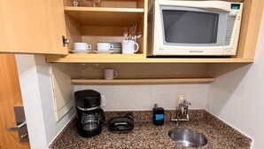 A compact kitchenette with a microwave, coffee maker, and a small refrigerator. - Flat Let's Idea - Centro de Brasília (Brasília)