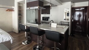 A modern kitchen with a central island, bar stools, a microwave, and a sink. - TOWN ROYAL 701 (Sapporo)