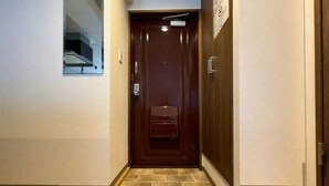 A hallway with a wooden door, a small window, and a tiled floor. - TOWN ROYAL 701 (Sapporo)