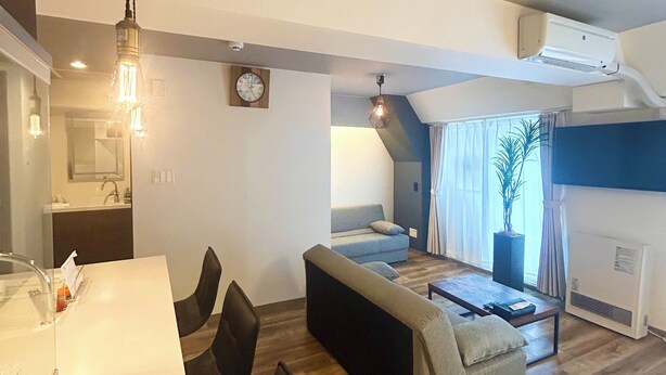 A modern living room with a sofa, a dining area with chairs, a kitchen in the background, and a large window with curtains. - TOWN ROYAL 701 (Sapporo)