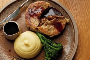 A plate with a meat patty, sauce, and a side of broccoli. - Bishopstrow Hotel and Spa - Small Luxury Hotels of the World (Bishopstrow)