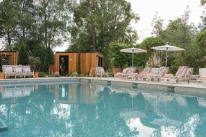 A swimming pool with lounge chairs and umbrellas, surrounded by trees. - Bishopstrow Hotel and Spa - Small Luxury Hotels of the World (Bishopstrow)