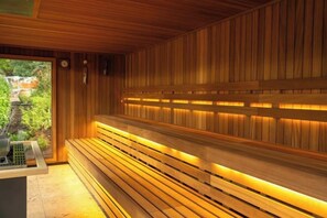 Una sauna con panche in legno e vista sul verde circostante.