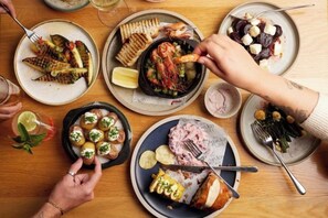 Een eettafel met diverse gerechten, waaronder zeevruchten, brood en salades.