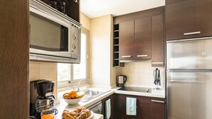 A modern kitchen with dark wooden cabinets, stainless steel appliances, and a breakfast setup including croissants and orange juice. - Benalmadena Principe 3p4p Balcon (Benalmádena)