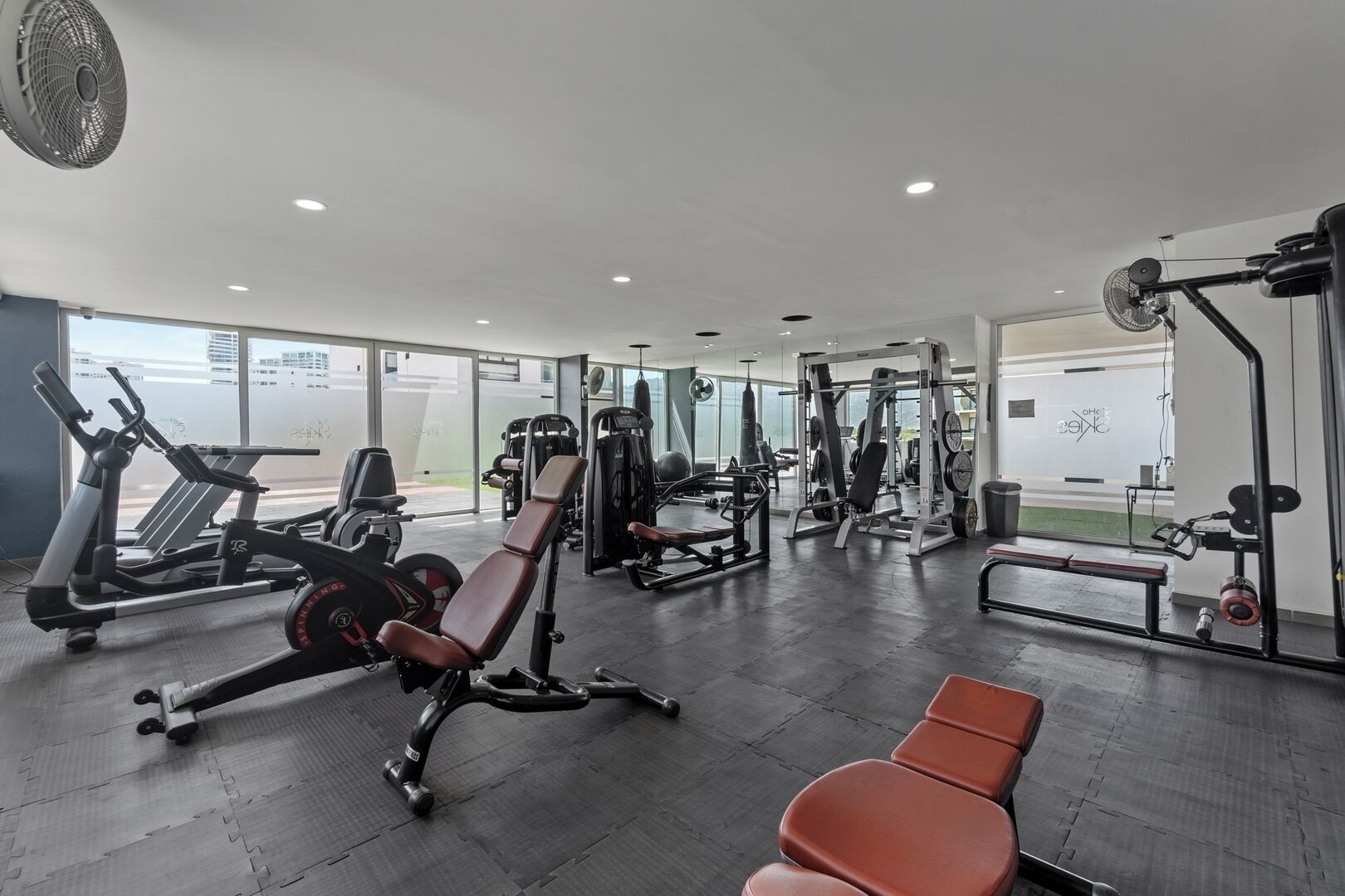 Ett modernt gym med konditionsmaskiner, styrketräningsutrustning och träningsbänkar.