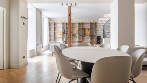 Un comedor moderno con una mesa redonda y sillas, una estantería de madera y una escalera que sube a un nivel superior.