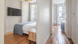 Un dormitorio moderno con cama, televisión y un ventanal grande.