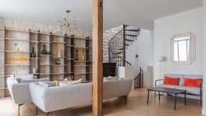 Una sala de estar moderna con un sofá gris, una mesa de centro de madera y una escalera que lleva a una zona superior.