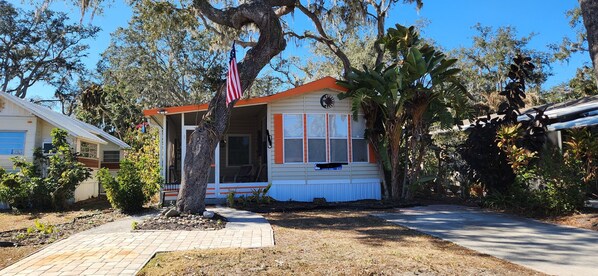 A small house with a porch, a flag, and a garden.