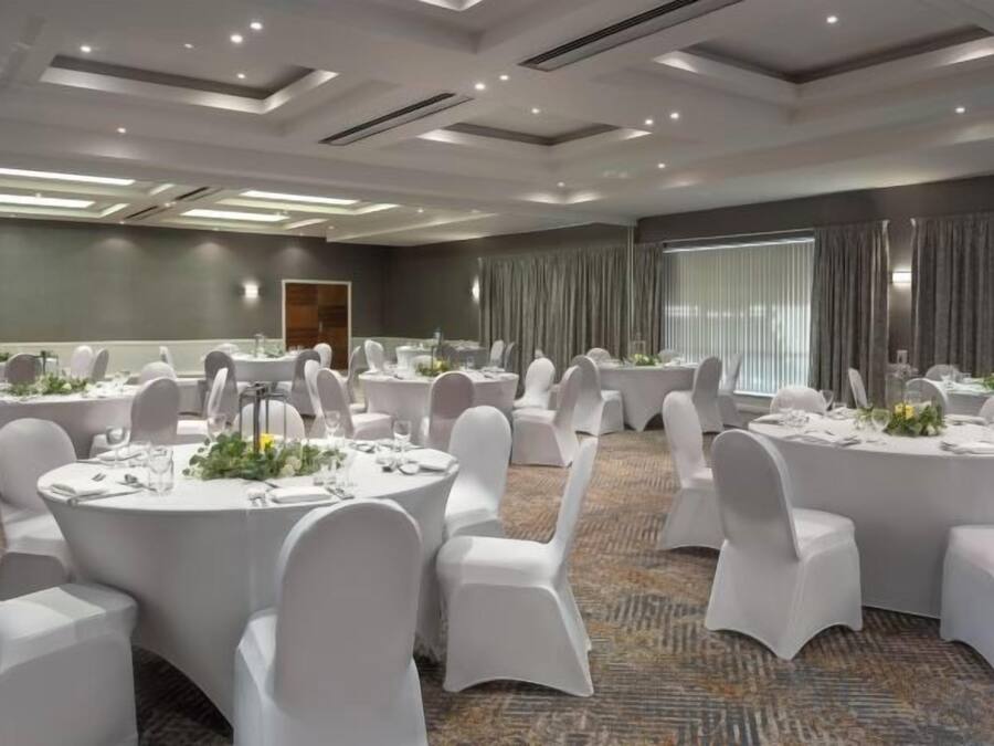 A conference room with round tables, white chairs, and a carpeted floor.