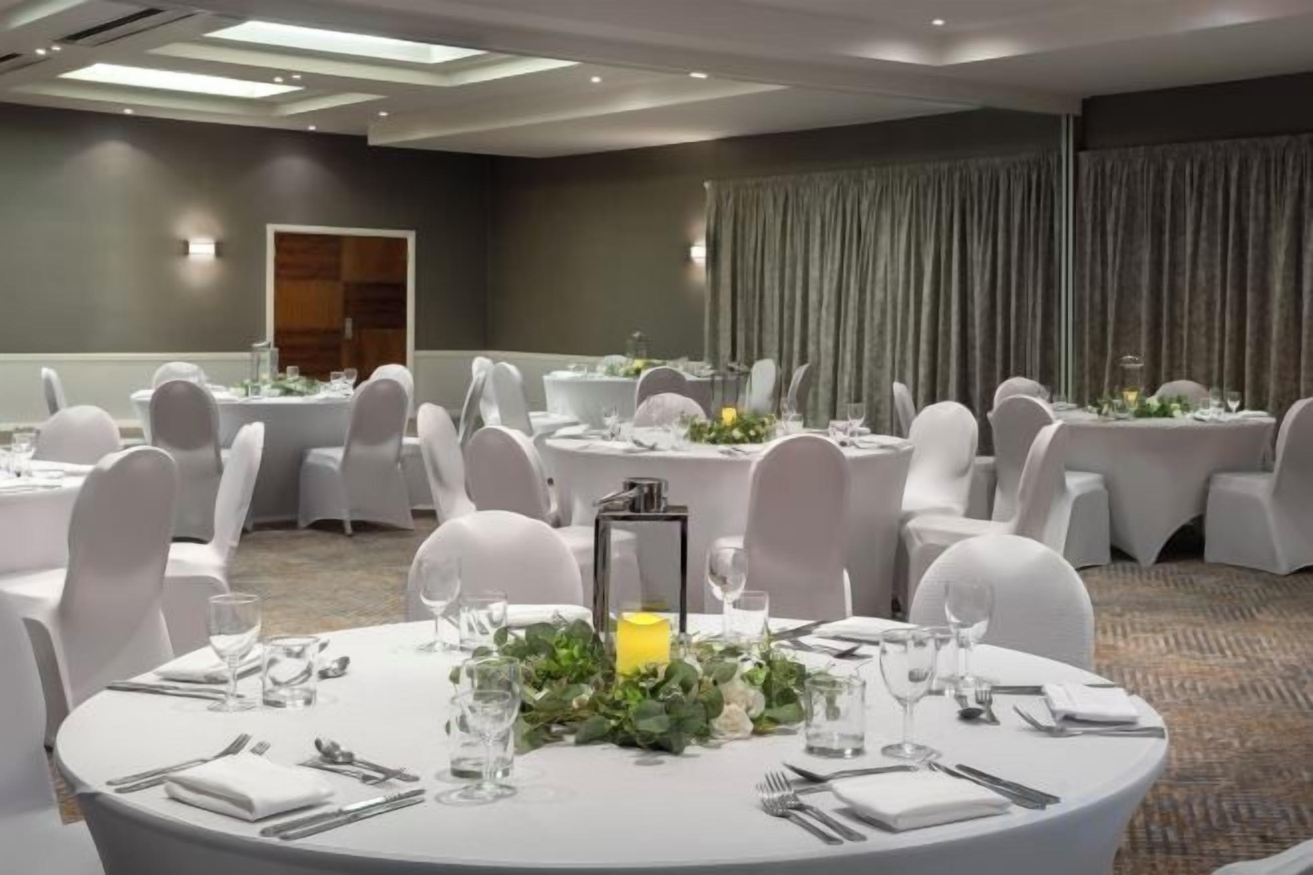 A conference room with round tables, white chairs, and a carpeted floor.