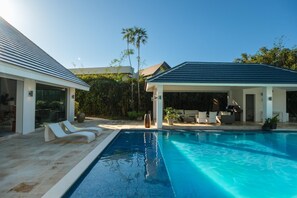 Ein modernes Haus mit Swimmingpool, überdachter Sitzgelegenheit und einer Terrasse mit Liegestühlen.