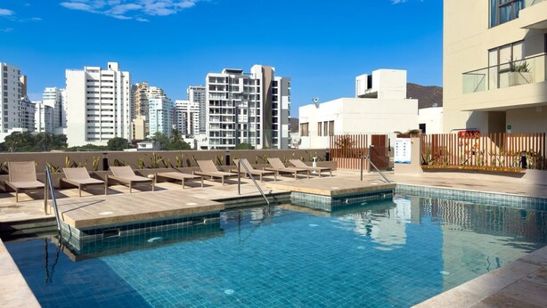 Une piscine sur le toit, dotée de chaises longues et offrant une vue sur la ville.
