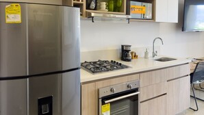 Une cuisine moderne équipée d’un réfrigérateur en acier inoxydable, d’une cuisinière à gaz, d’un four et d’une machine à café.
